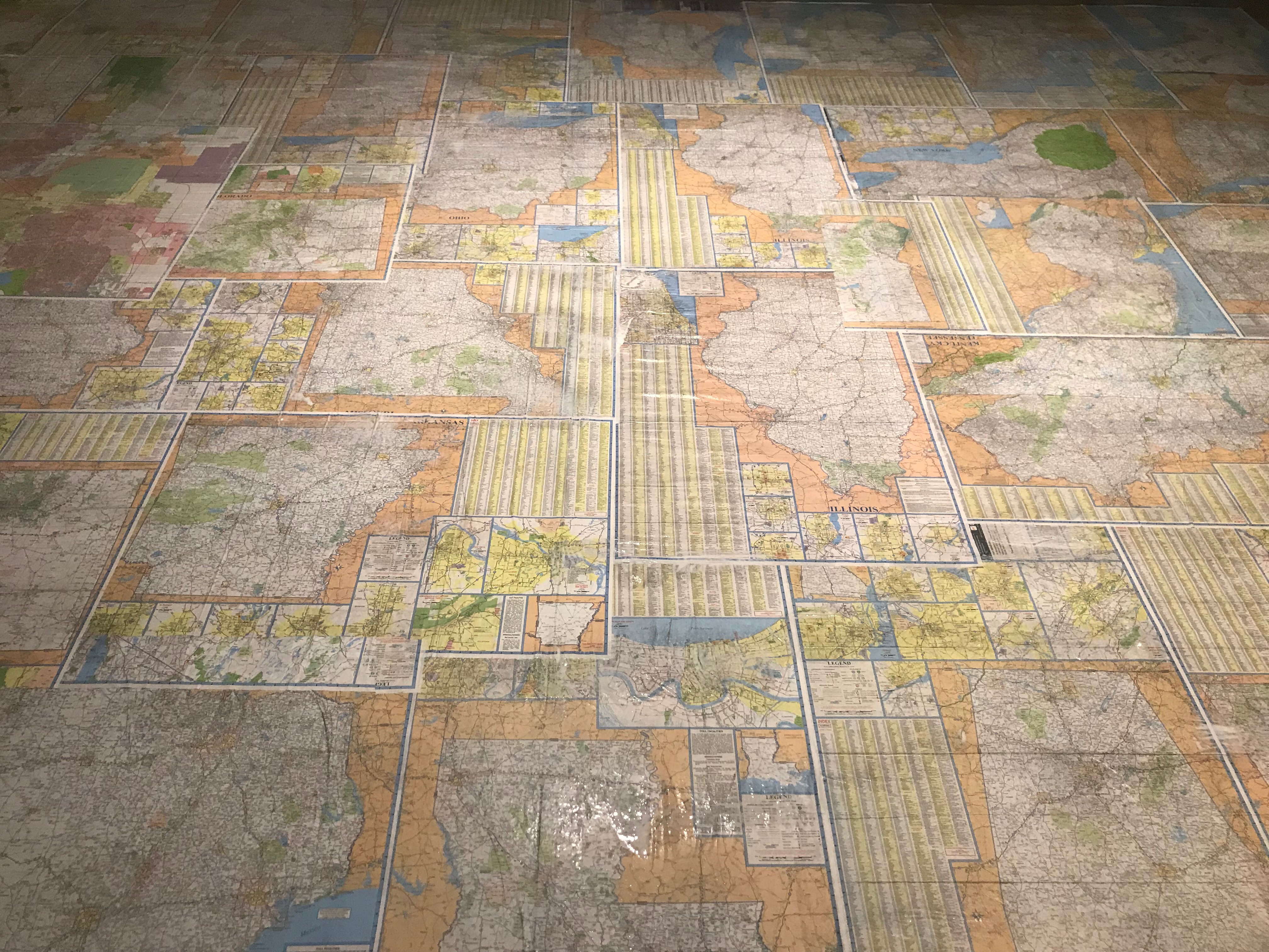Image of floor installation with collage of US road maps on plywood